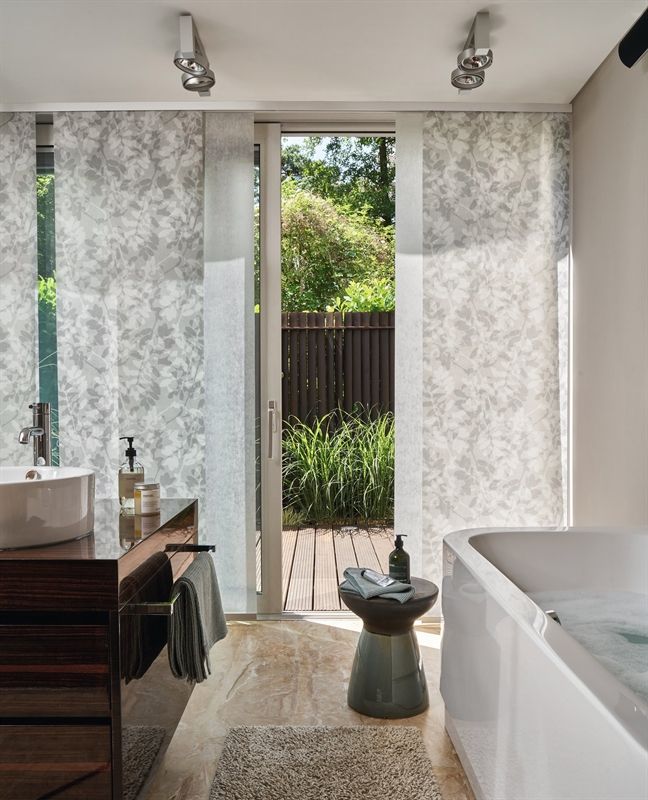 Ein Badezimmer mit Waschbecken und Badewanne sowie einer Glasschiebetür