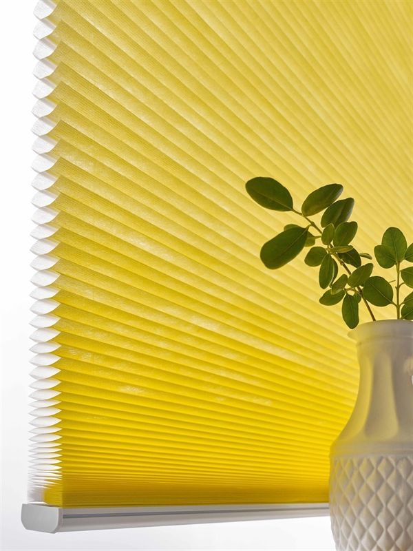 Eine gelbe Jalousie mit einer Pflanze in einer Vase darunter