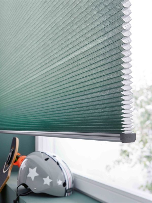 Auf einem Fensterbrett neben einer grünen Jalousie liegt ein Helm.