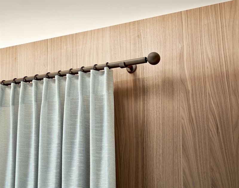 Ein Paar Vorhänge, die an einer Holzwand hängen.