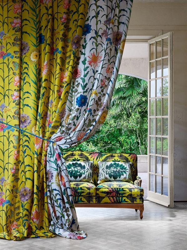 Eine Couch steht hinter einem gelben Vorhang mit Blumen darauf