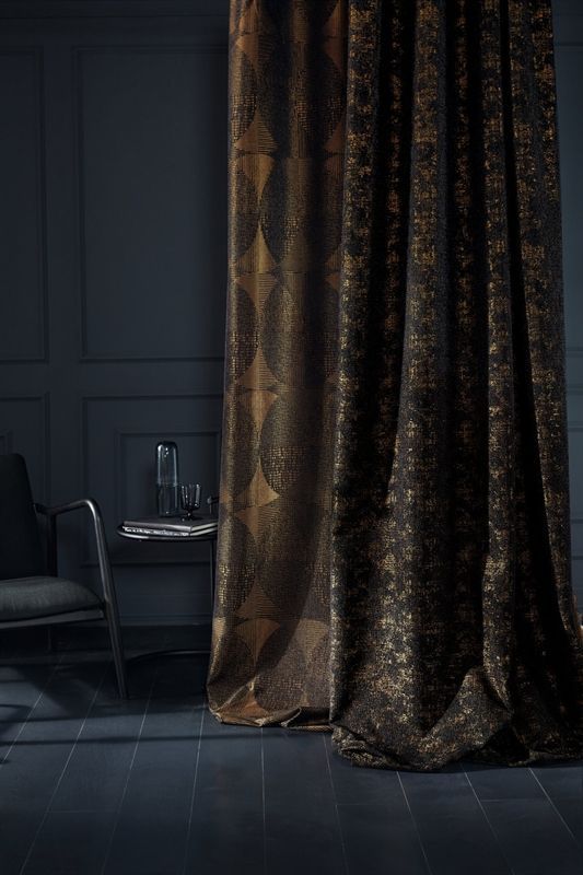 In dem Zimmer mit schwarzen Vorhängen stehen ein Stuhl und ein Tisch.