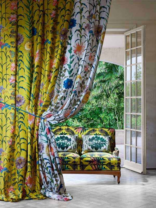 Eine Couch steht hinter einem gelben Vorhang mit Blumen darauf