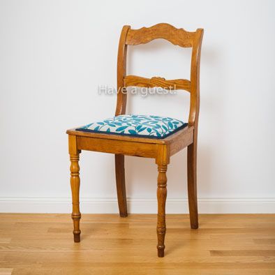 Ein Holzstuhl mit blauem Kissen steht auf einem Holzboden