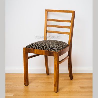 Ein Holzstuhl mit schwarzem Kissen steht auf einem Holzboden