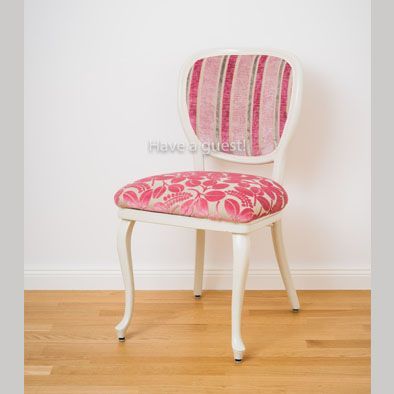 Ein Stuhl mit rosa und weiß gestreifter Rückenlehne steht auf einem Holzboden