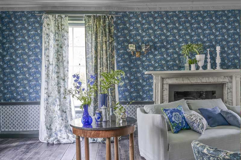 Ein Wohnzimmer mit Couch, Sessel, Tisch und Kamin.