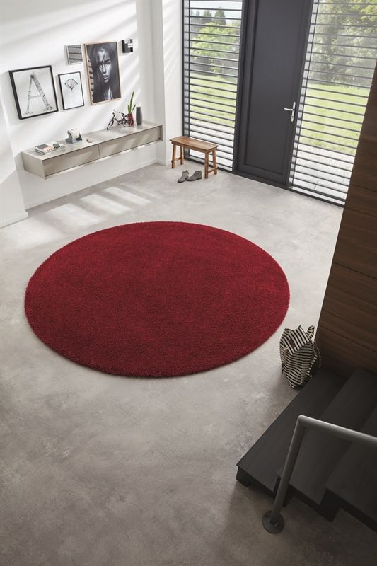 Ein runder roter Teppich liegt auf dem Boden in einem Wohnzimmer