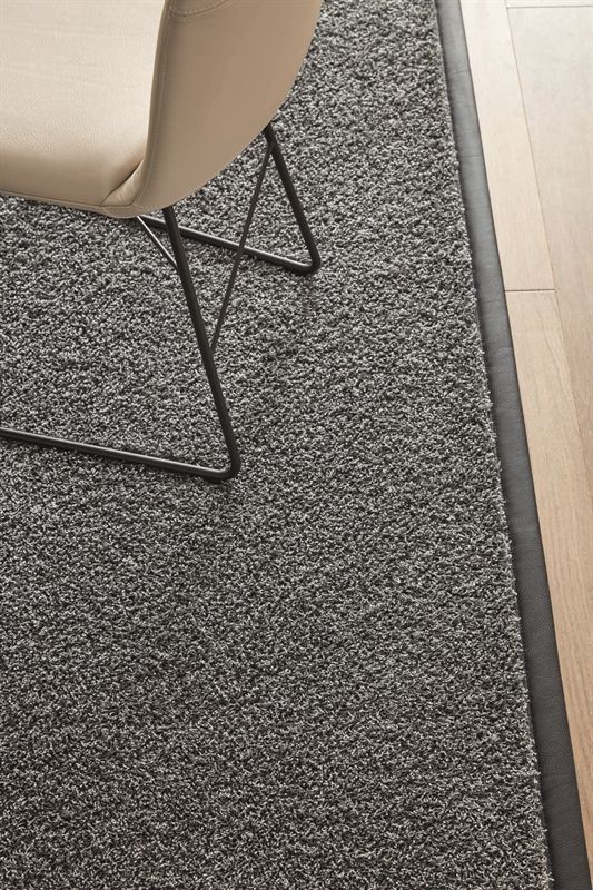 Ein Stuhl steht auf einem grauen Teppich neben einem Holzboden.