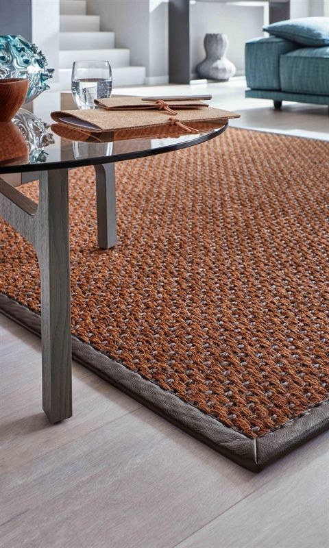 Ein Wohnzimmer mit einem Teppich und einem Glastisch
