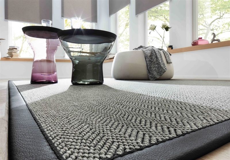 Ein Wohnzimmer mit einem Teppich und einer Vase auf dem Boden