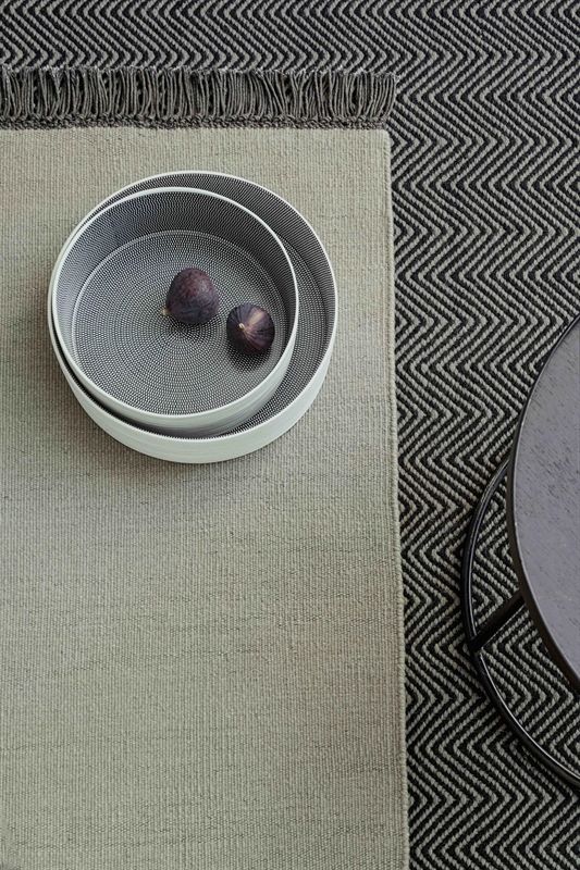 Eine Schale mit Feigen steht auf einem Couchtisch neben einem Teppich.