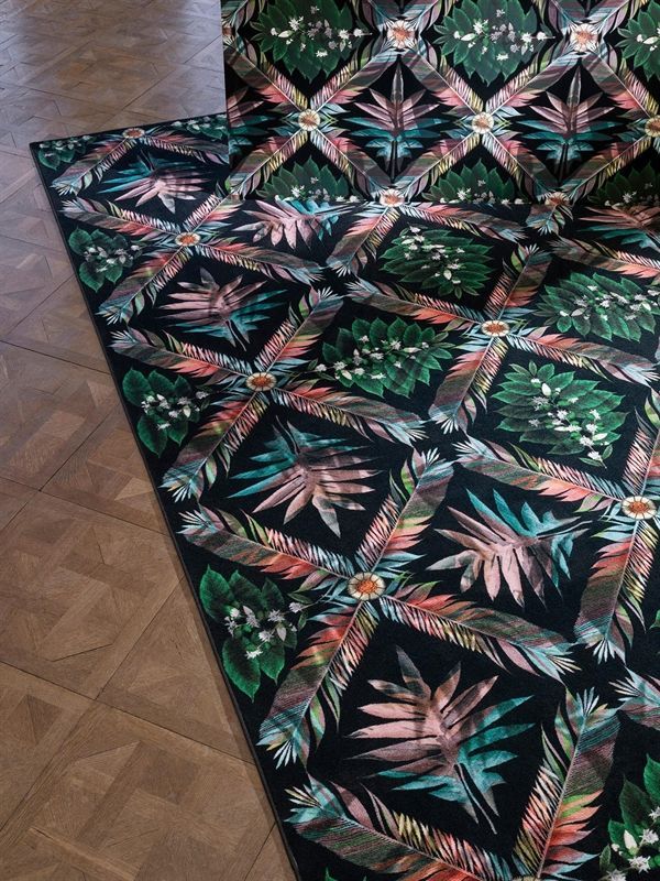 Auf einem Holzboden liegt ein Teppich mit Blumenmuster.