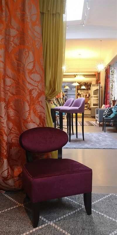 In einem Wohnzimmer stehen ein lila Sessel und ein Ottomane.