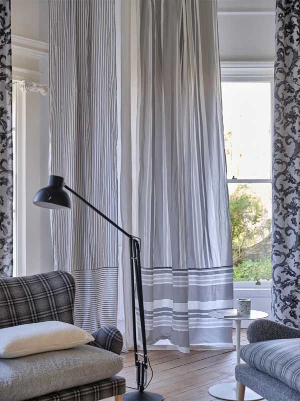 Ein Wohnzimmer mit gestreiften Vorhängen und einer Lampe