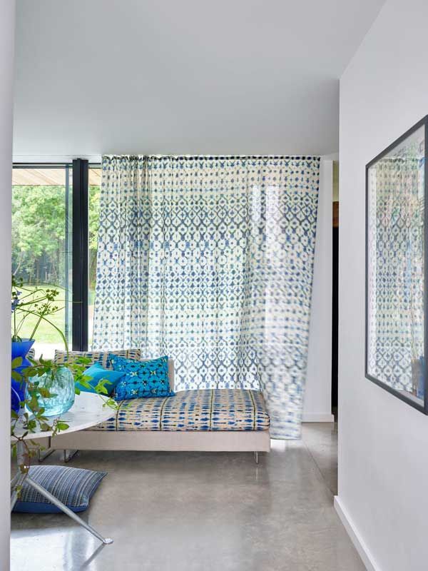 Ein Schlafzimmer mit blauen und weißen Vorhängen und einer Couch