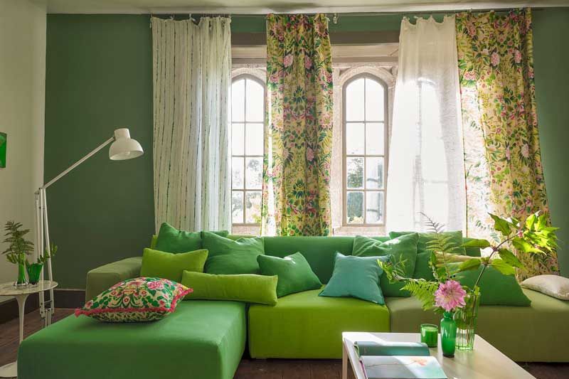 Ein Wohnzimmer mit grünen Vorhängen und einer grünen Couch