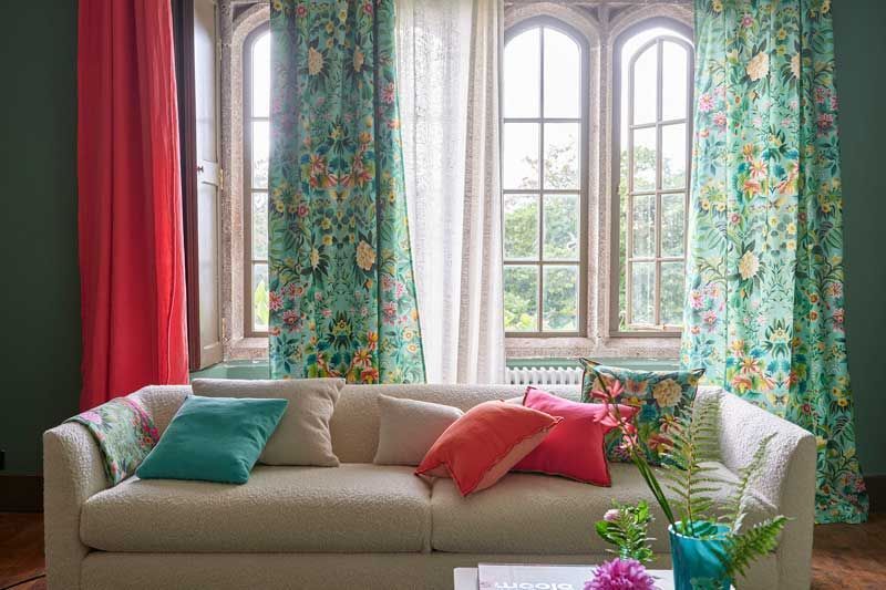 Ein Wohnzimmer mit einer Couch, Vorhängen und einem Fenster.