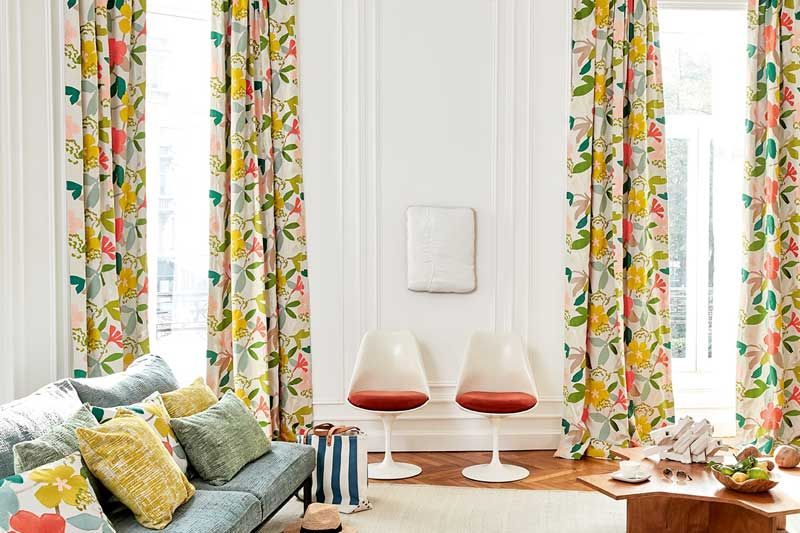 Ein Wohnzimmer mit einer blauen Couch und geblümten Vorhängen