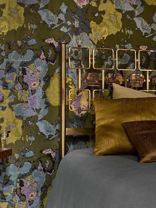 Ein Bett mit einer Blumentapete an der Wand dahinter