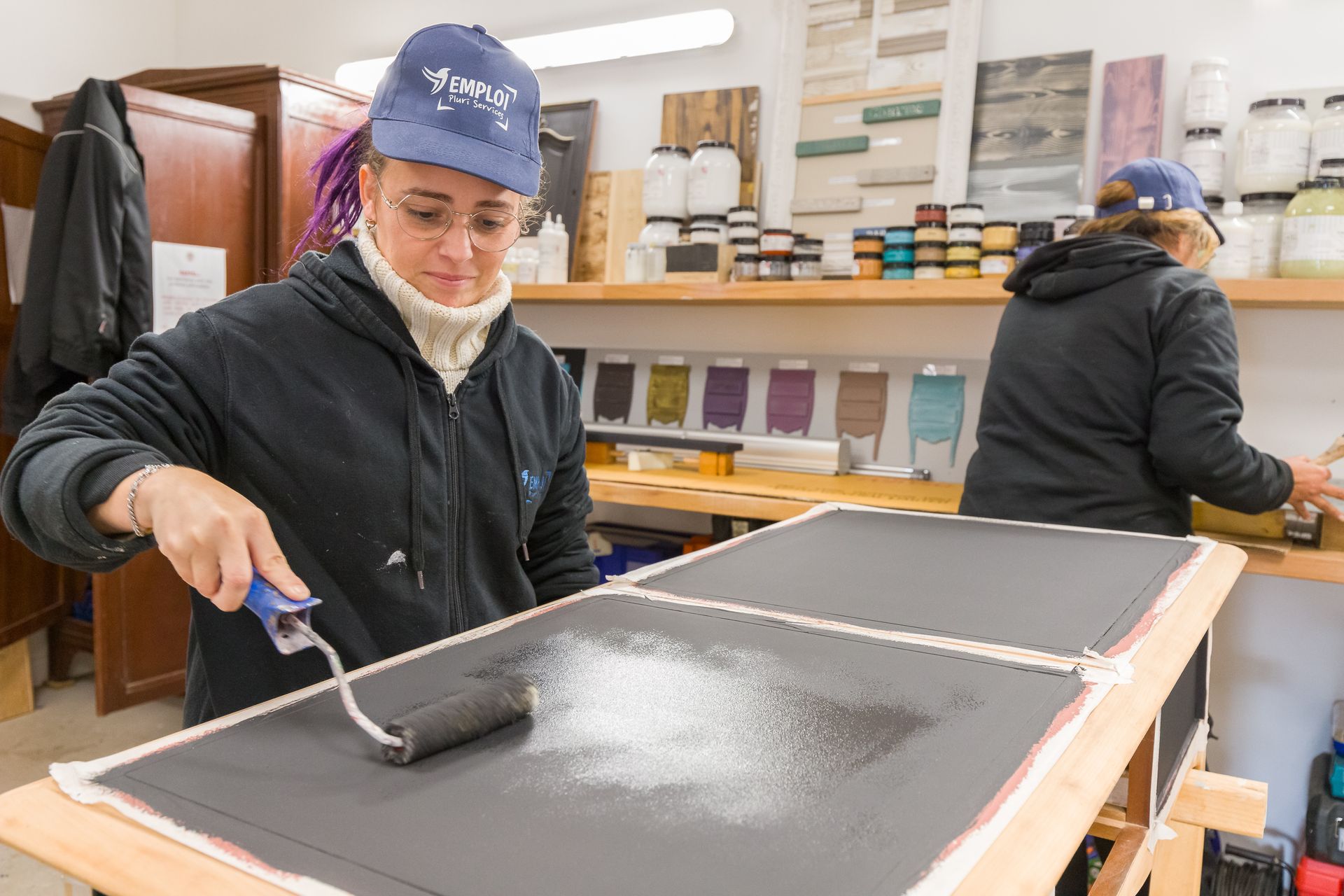 Professionnelle d'EMPLOI PLURI-SERVICES peignant un meuble