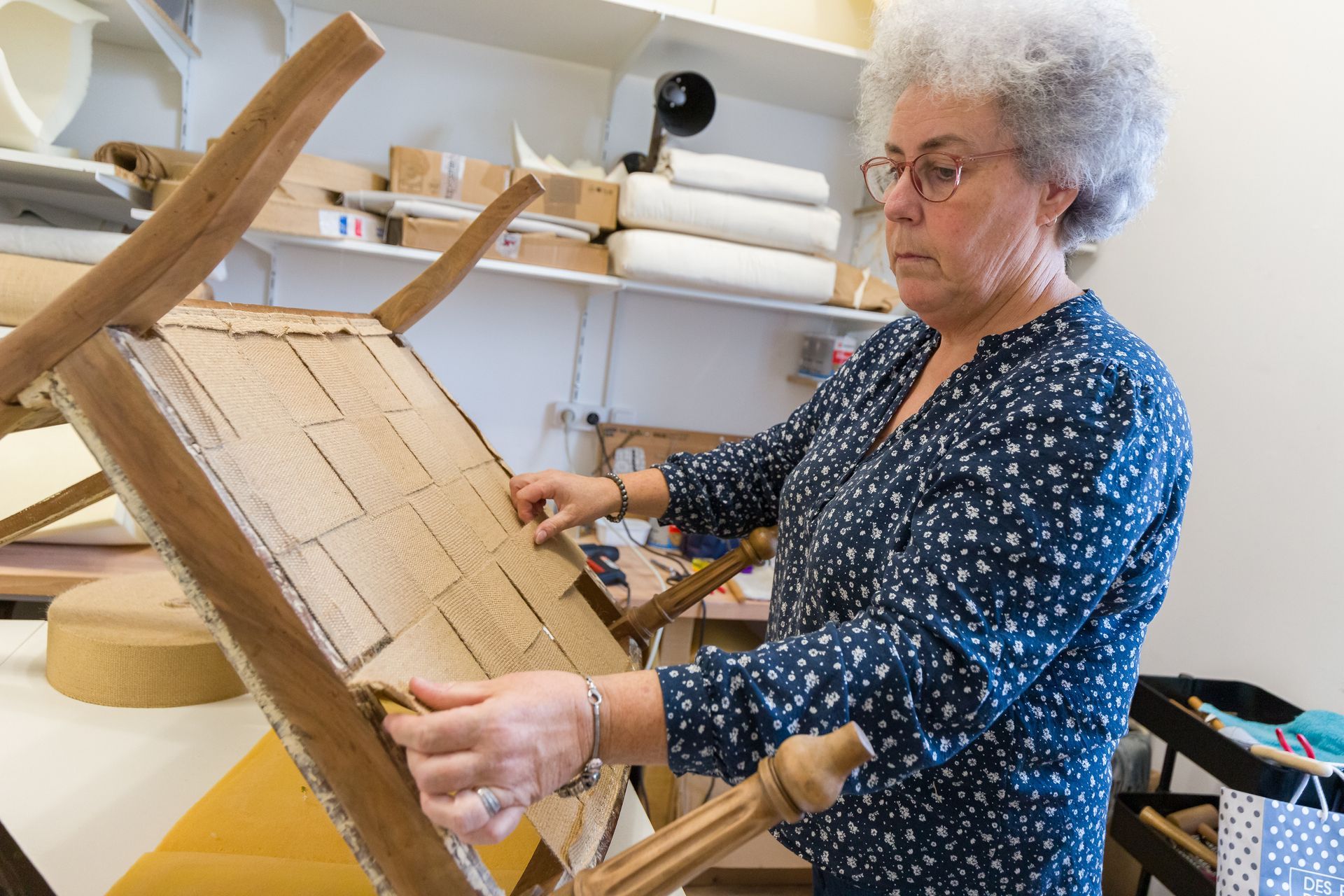 Professionnelle d'EMPLOI PLURI-SERVICES réparant le dessous d'une chaise