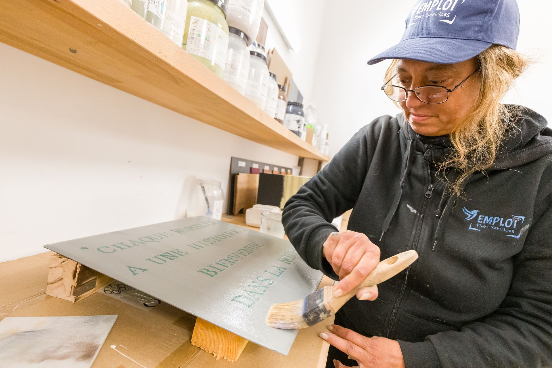 Professionnelle d'EMPLOI PLURI SERVICES peignant une plaque lors d'un atelier