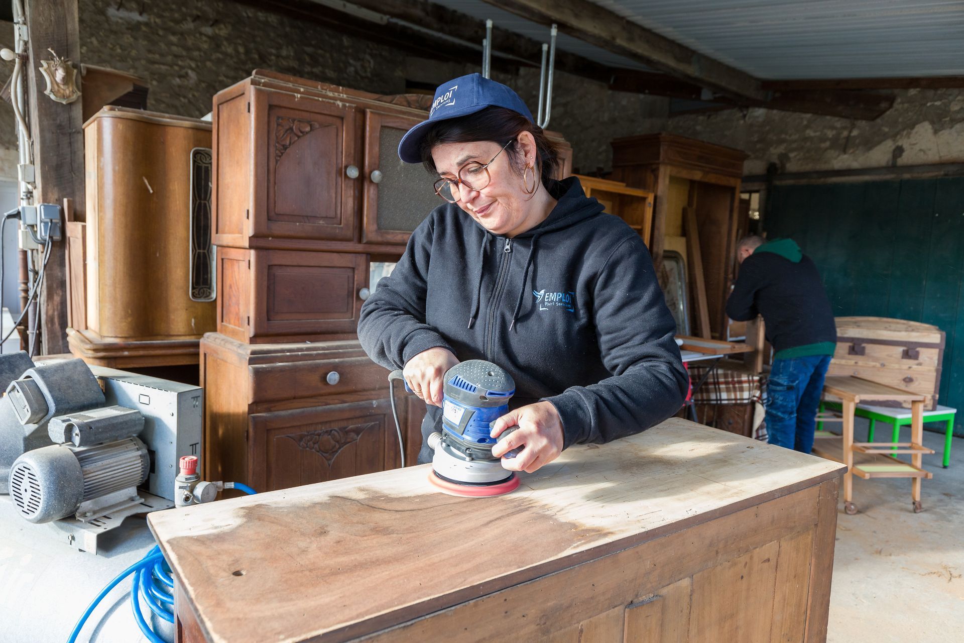 Professionnelle d'EMPLOI PLURI-SERVICES ponçant un meuble