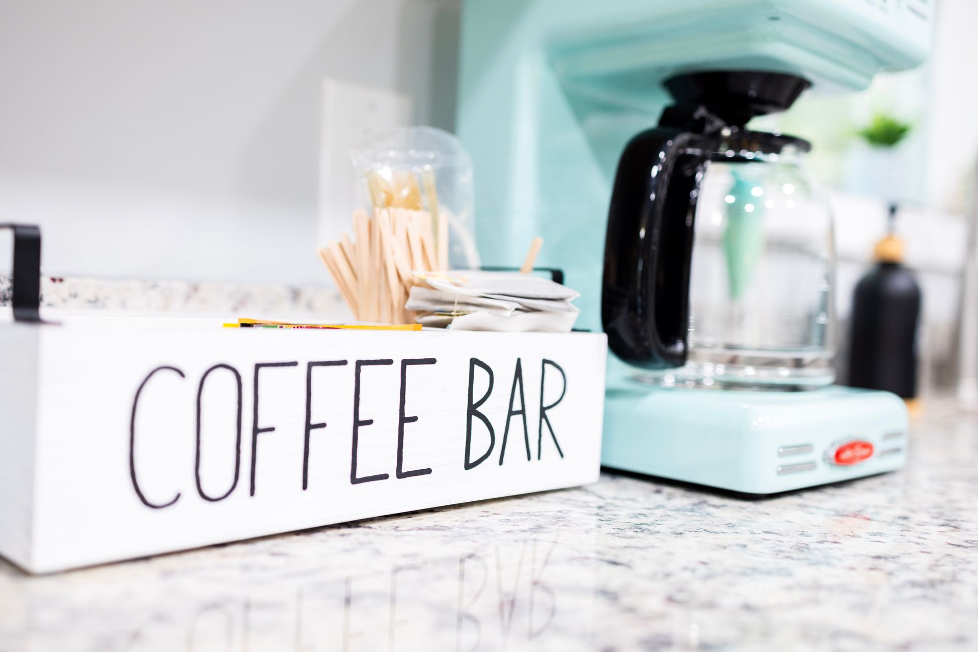 A coffee bar is sitting on a counter next to a coffee maker.
