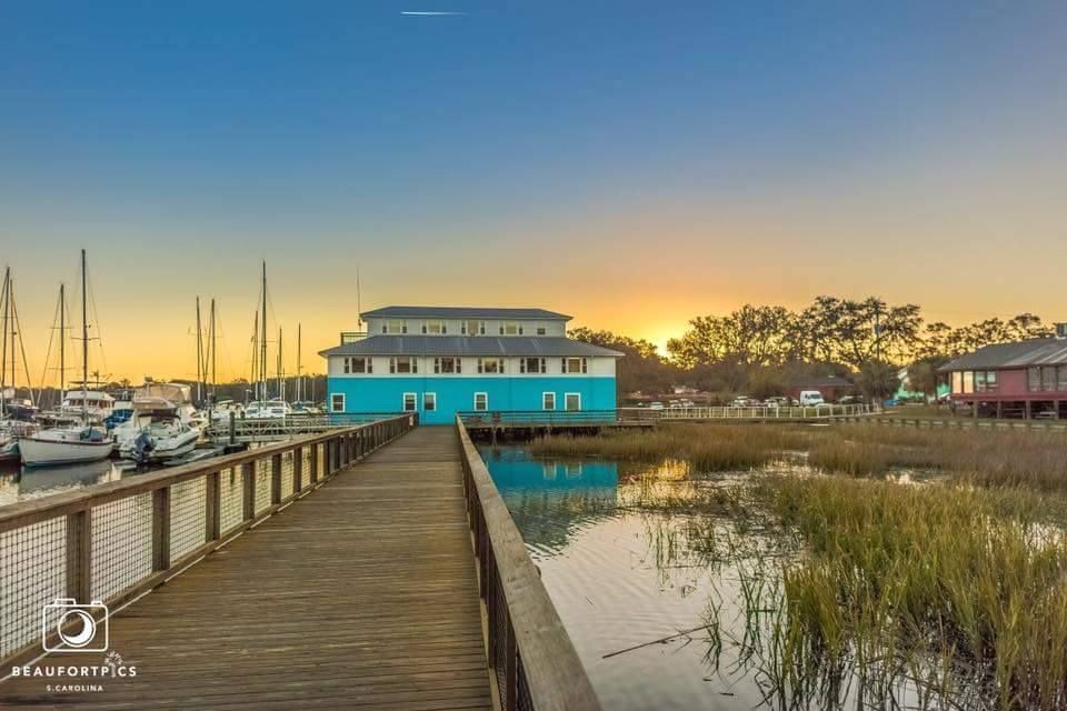 A wooden walkway leading to a blue building next to a body of water.