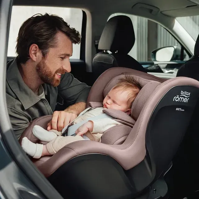 Un hombre sostiene a un bebé en un asiento de coche Britax.