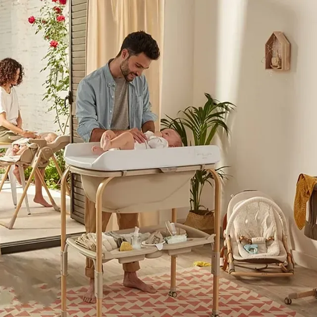 Un hombre está cambiando el pañal de un bebé en una habitación.