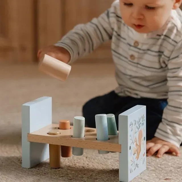 Un bebé está jugando con un juguete de madera en el suelo.