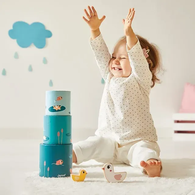Una niña está sentada en el suelo con las manos en el aire.