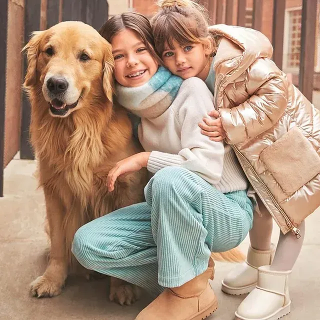 Dos niñas posan para una foto con un perro.