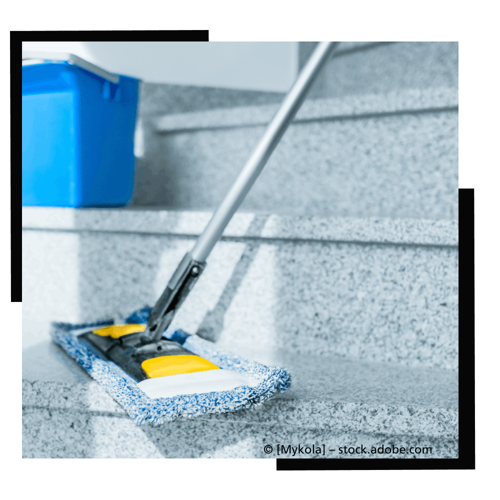 Person im Schutzanzug reinigt eine Edelstahloberfläche im Labor.