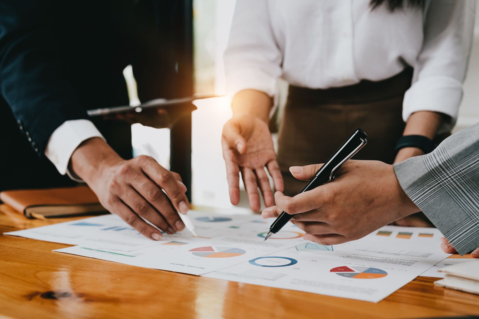 Tres personas colaborando en gráficos y diagramas, discutiendo datos.