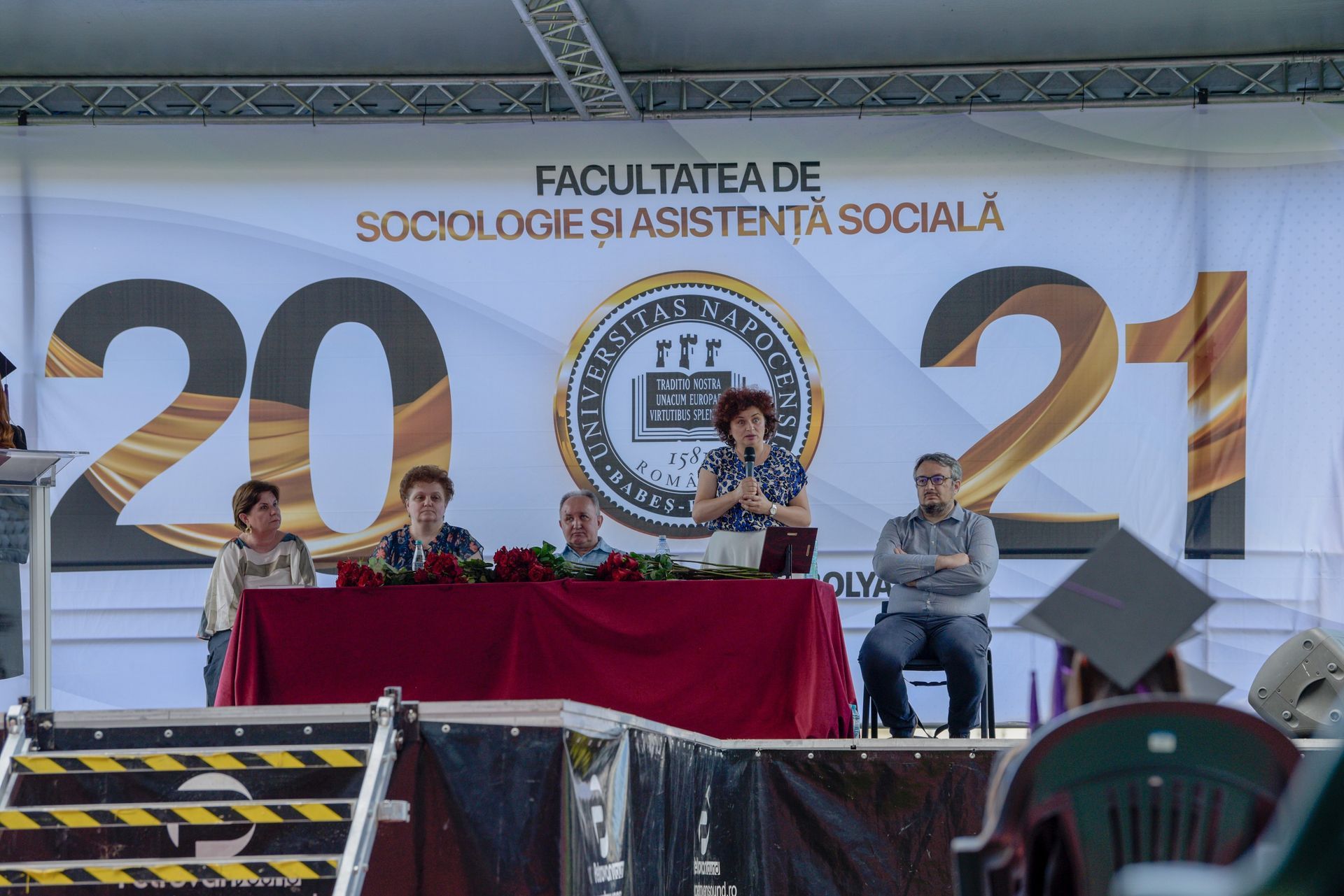 Panel de ponentes en un escenario bajo una pancarta con el número “2021” en la Facultad de Sociología y Trabajo Social.