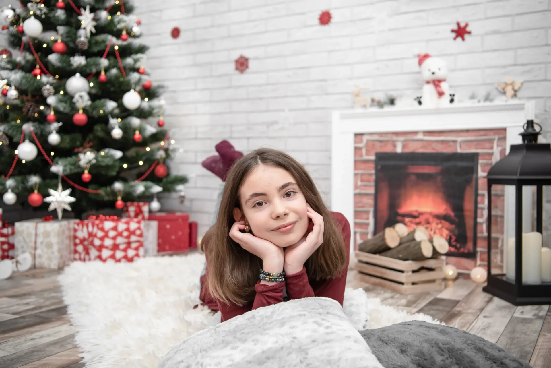 Una persona apoya la barbilla en las manos junto a un árbol de Navidad decorado y una chimenea en una acogedora sala de estar.