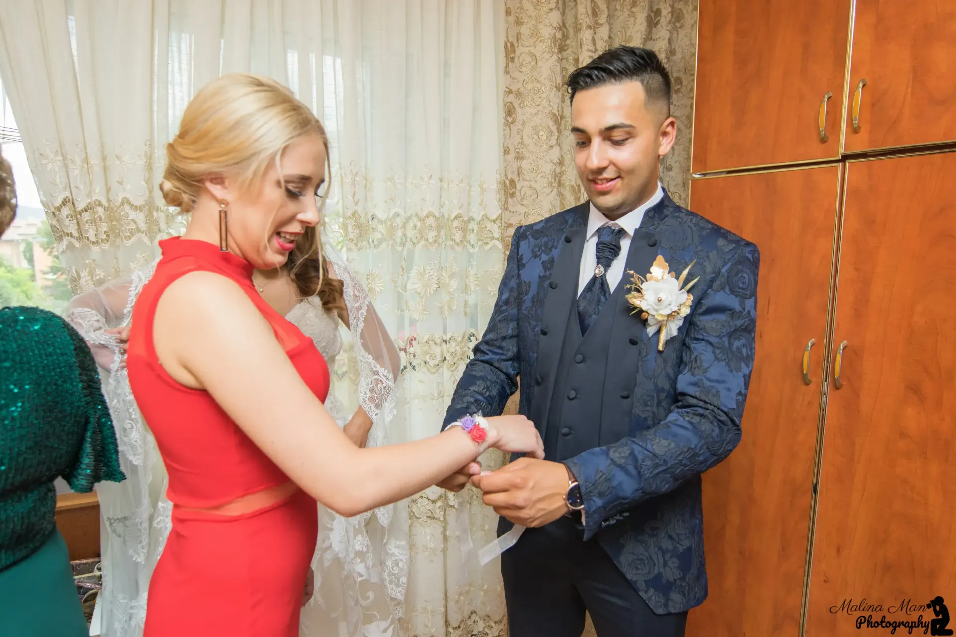 La novia, vestida de rojo, coloca un anillo en el dedo del novio durante la ceremonia nupcial en el interior del edificio.