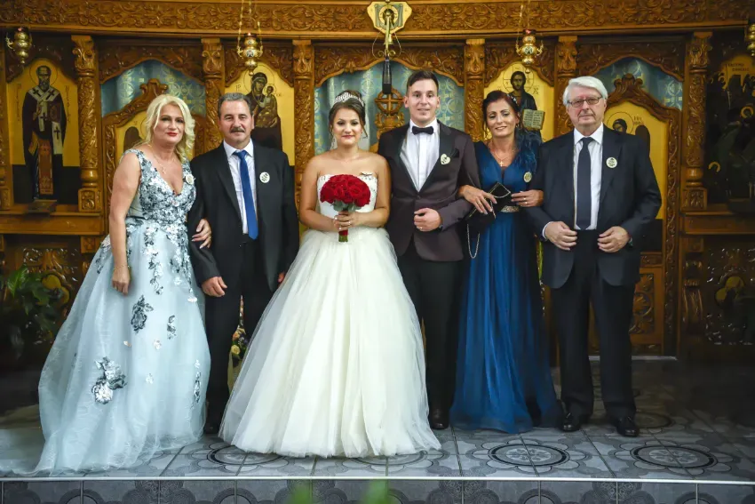 Cinco personas vestidas de gala posan juntas en una habitación ornamentada y decorada en oro.