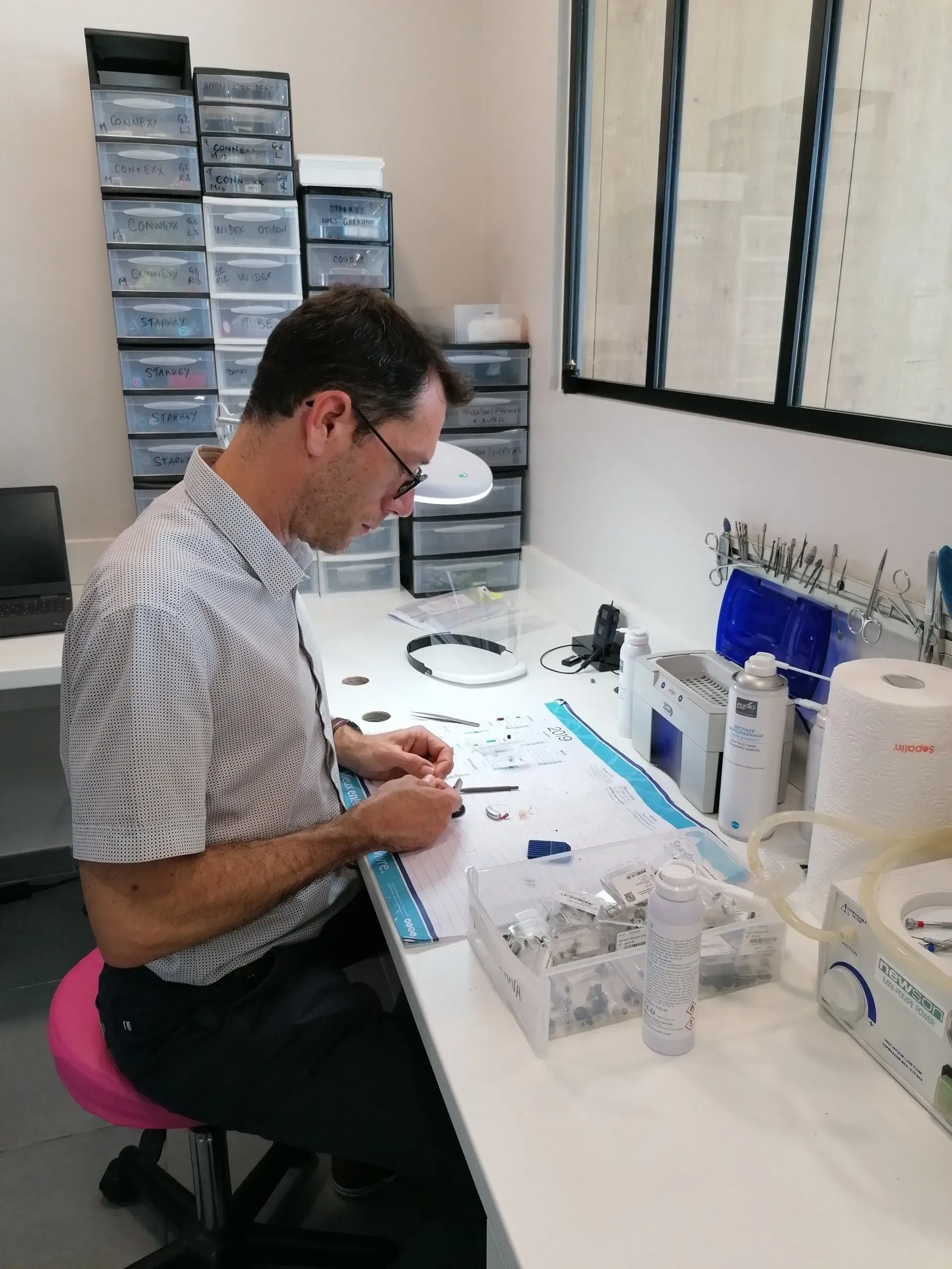 Personne travaillant à un bureau avec de petites pièces dans un bureau ou un atelier lumineux