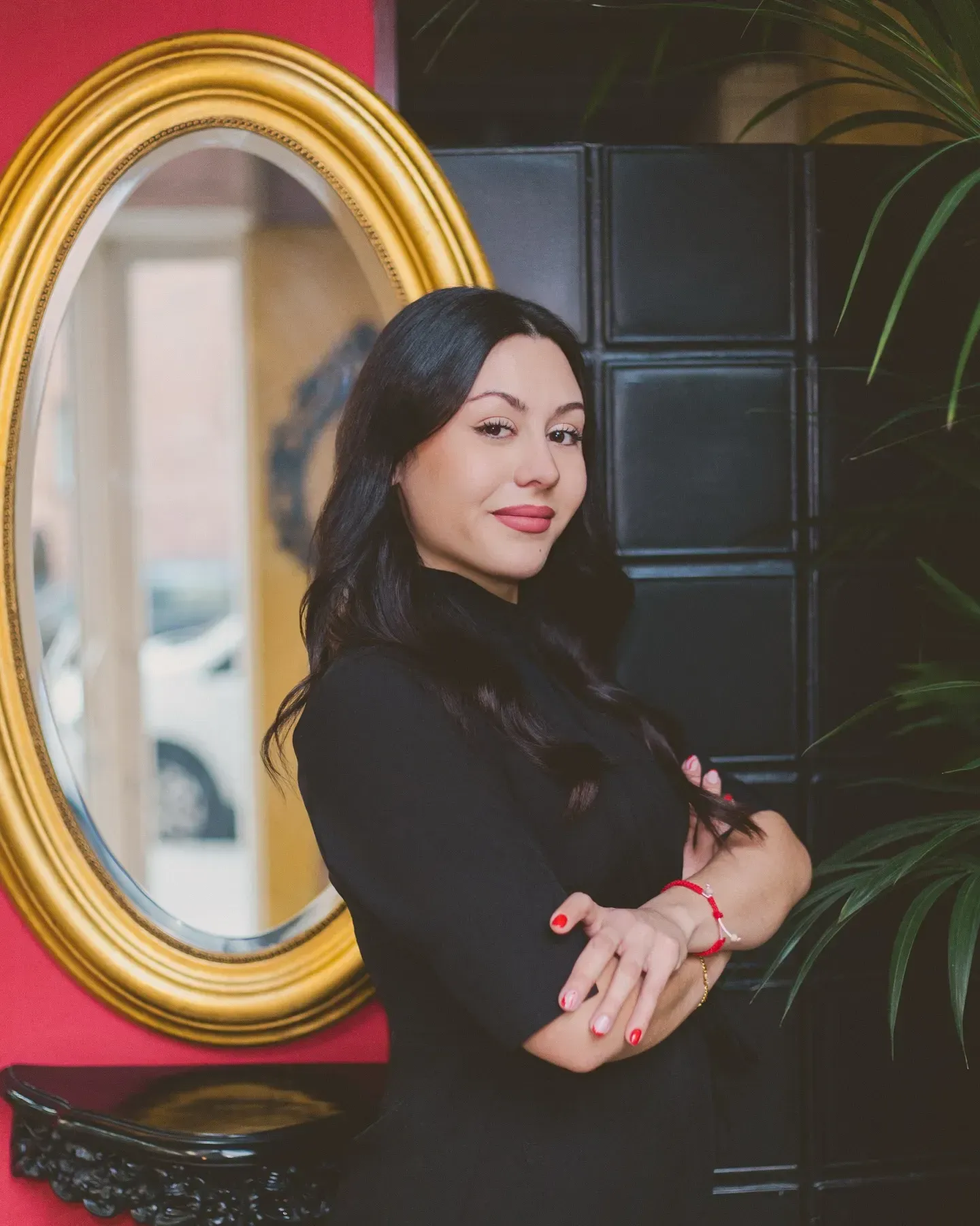 Mujer vestida de negro, con los brazos cruzados, sonríe.