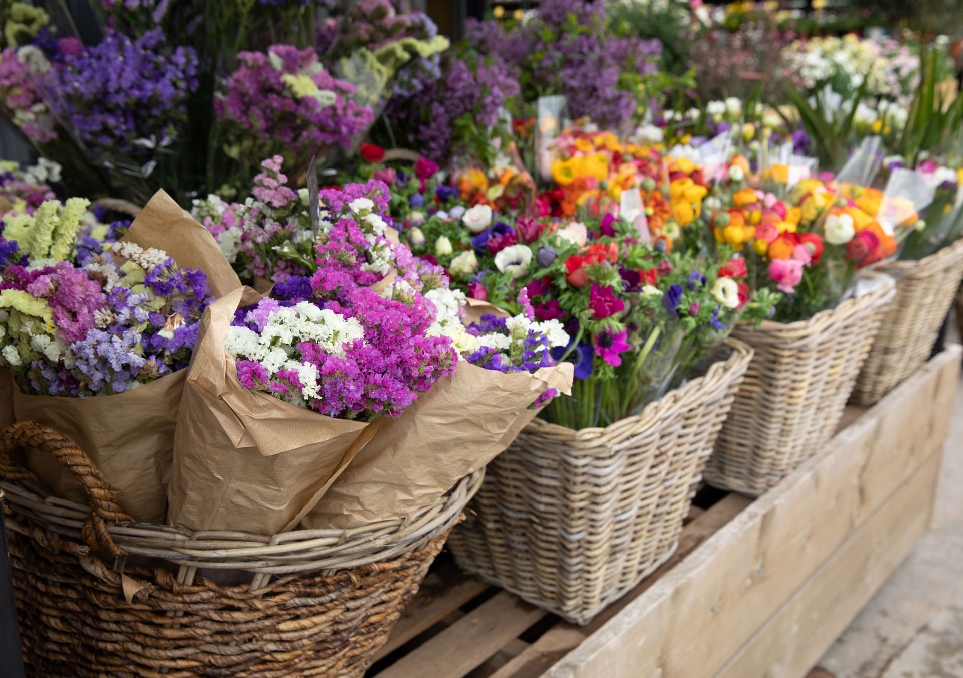 Auf einem Holzregal steht ein Strauß mit Blumenkörben.