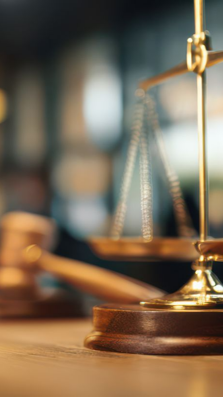 Balance et maillet de la justice sur une table en bois, dans un cabinet d'avocats.