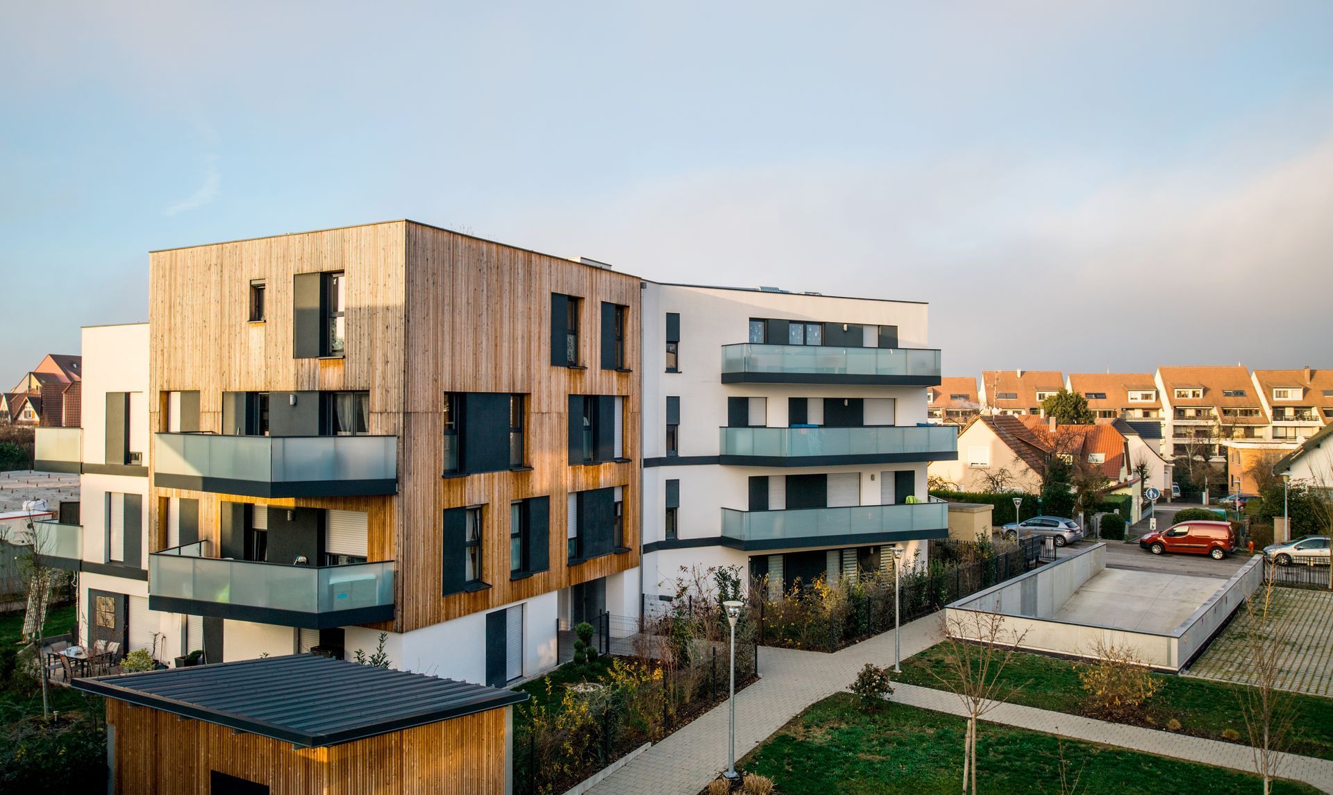 Immeubles d'appartements modernes aux façades en bois et blanches dans un quartier résidentiel au coucher du soleil