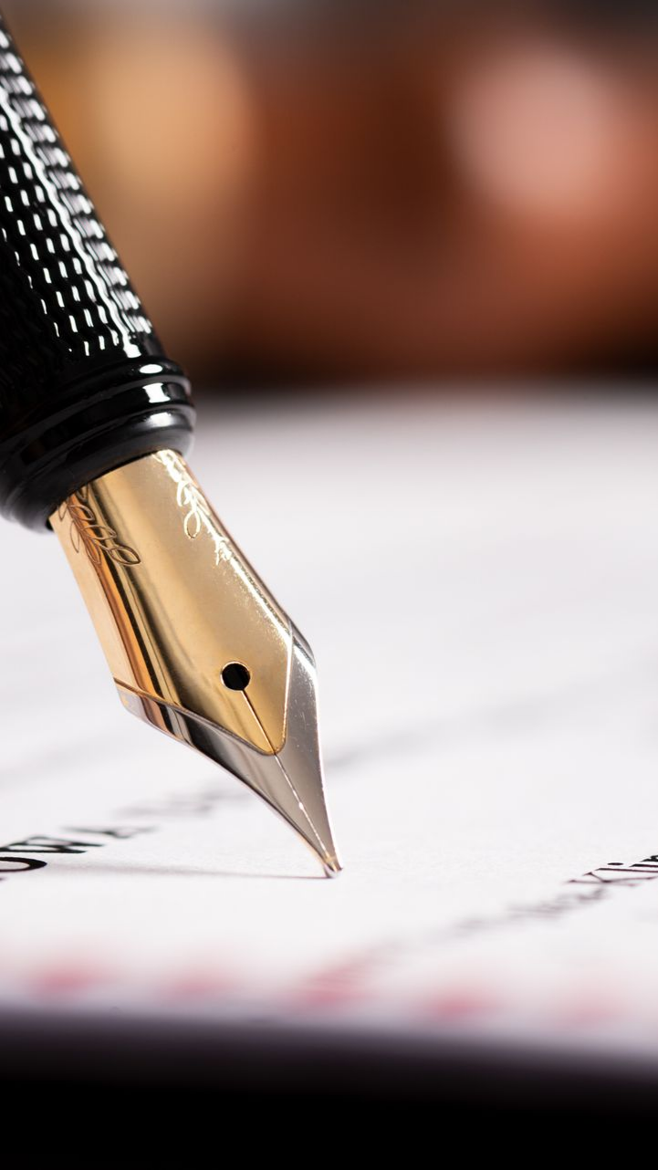 Stylo plume à plume dorée écrivant sur du papier blanc.
