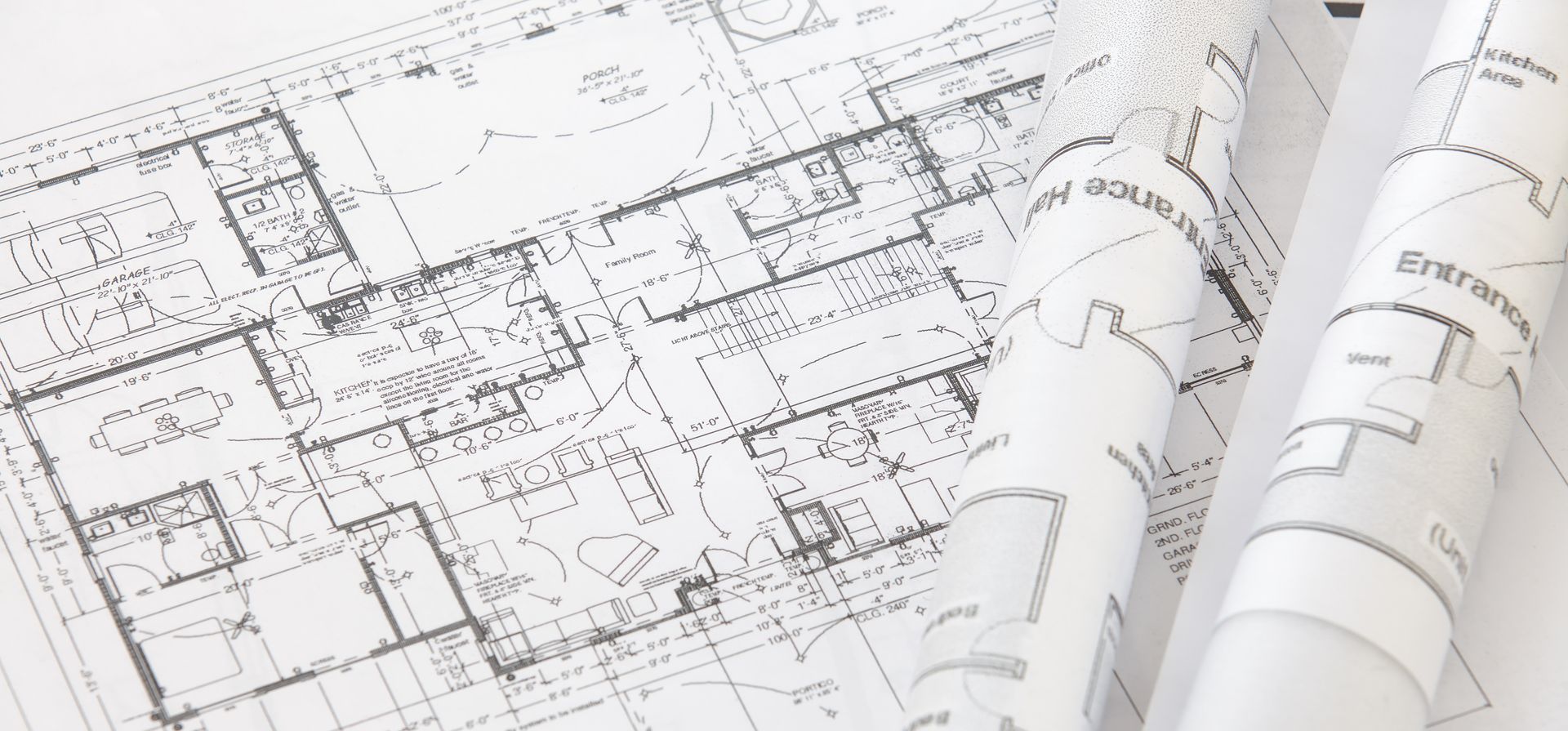 Plans architecturaux déroulés sur une table à dessin, montrant les plans d'étage et les croquis techniques.