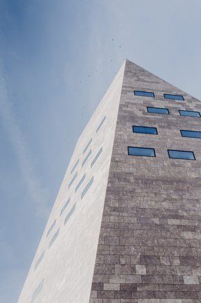 Een hoog, geometrisch gebouw met rechthoekige ramen tegen een helderblauwe hemel. Het Forum in Groningen
