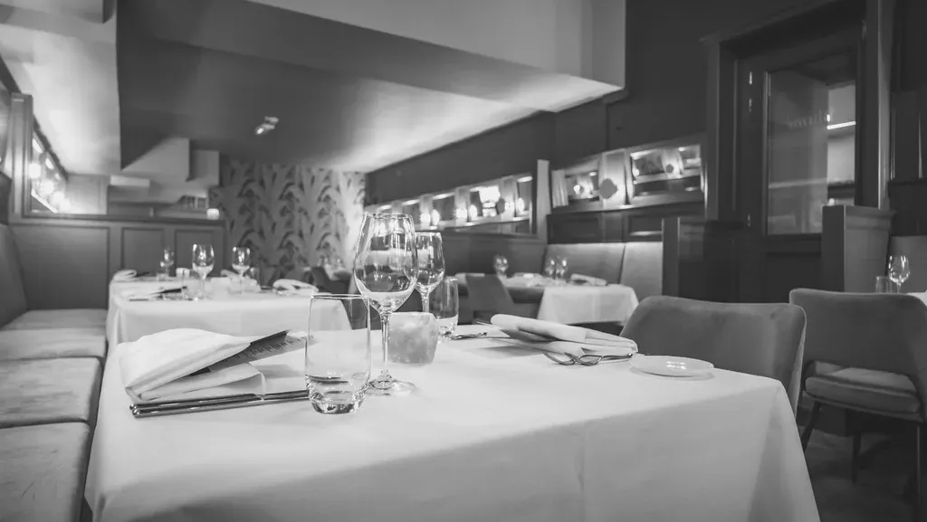 Een zwart-witfoto van een restaurant vol tafels en stoelen.